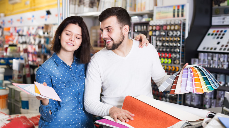 Young couple looking at paint swatches and materials at a hardware store