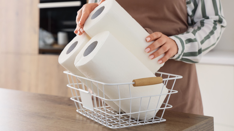 Someone placing paper towels in a wire basket.