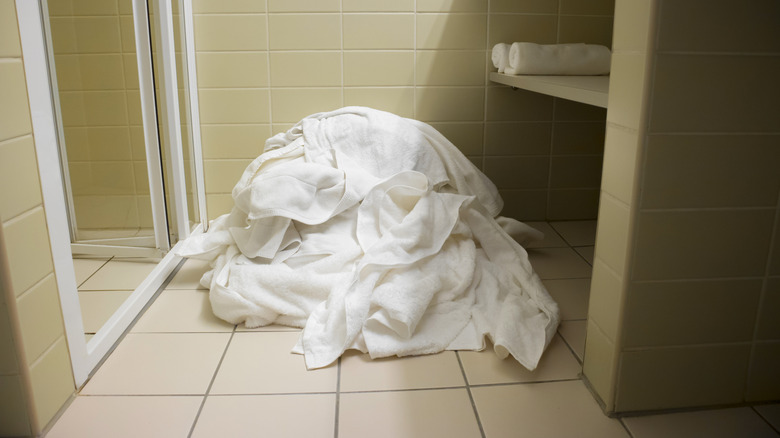 A pile of towels heaped on the bathroom floor