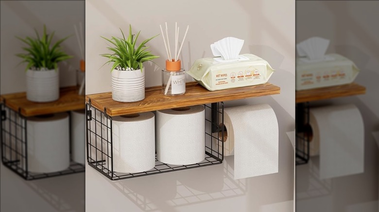 picture of toilet paper holder used to store two extra rolls of toilet paper, with a plant and wipes on top