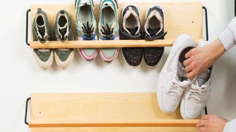 Someone putting shoes on a wall mounted rack.