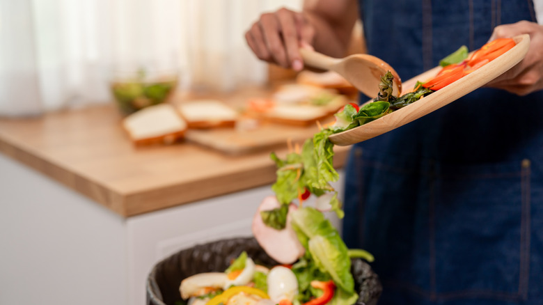 person throwing kitchen scraps away
