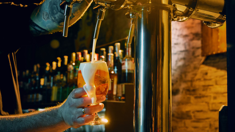 Man pouring beer into a glass from a tap.