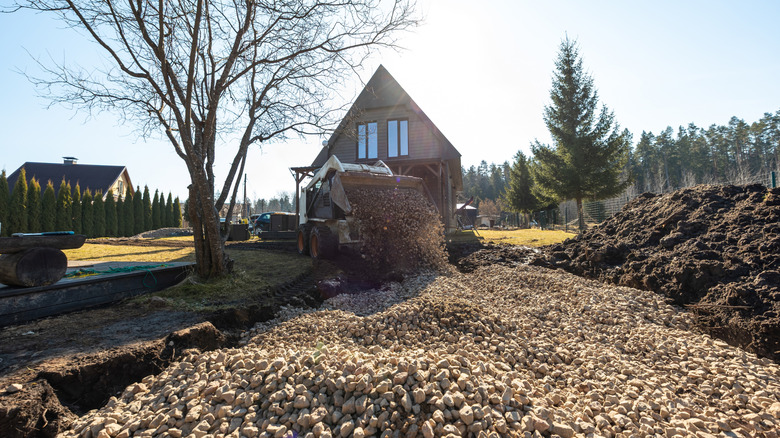 construction vehicle dumping crushed stone on a driveway.