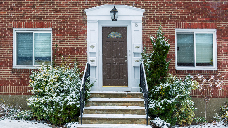A brick home with concrete front steps in the snow