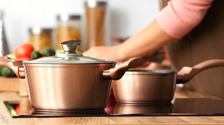 Person cooking with copper pots on the stovetop