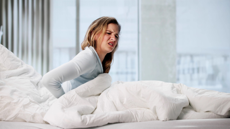 A woman sitting up in bed looking uncomfortable