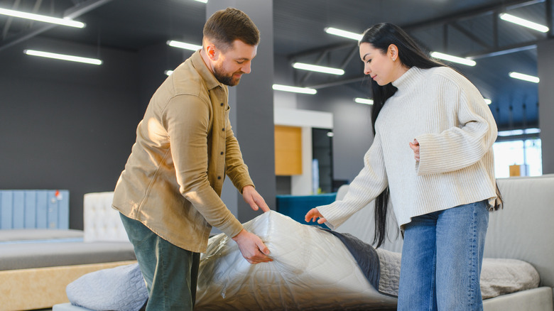 A couple inspecting a mattress in a store