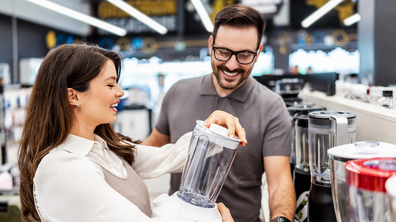 A smiling shop assistant helping a patron buy a blender