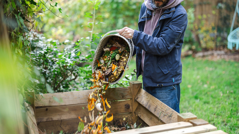A person throwing food scraps into compost bin