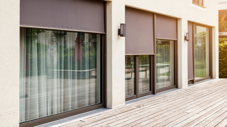Brown exterior shades rolled down over sliding glass doors and windows to block out the sun's heat.