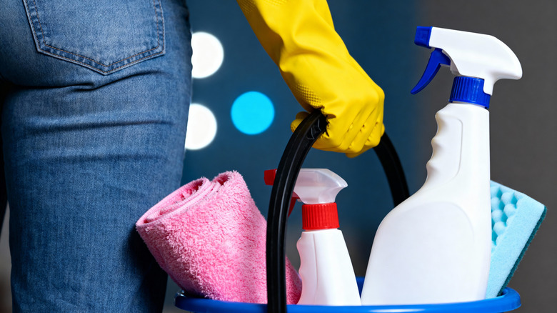 Back view of person holding a bucket with cleaning supplies