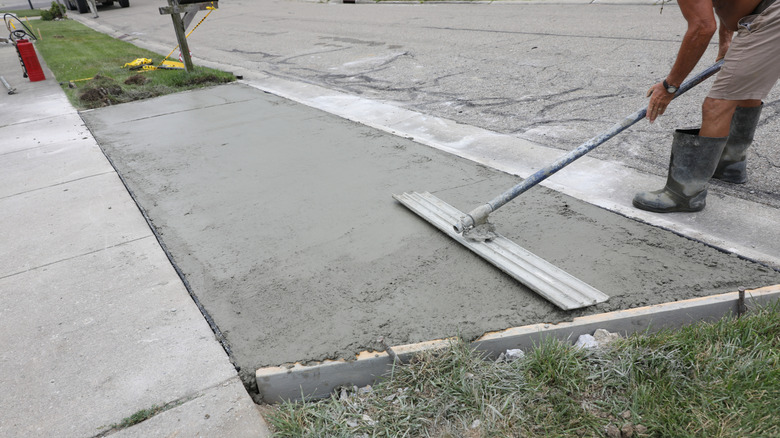 a worker smooths the driveway apron for a residence