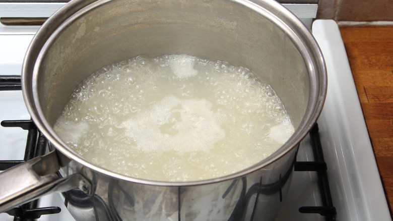 A pot of rice water boiling on a stove