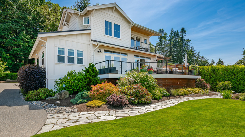 a modern two story home with an attractive landscape and driveway