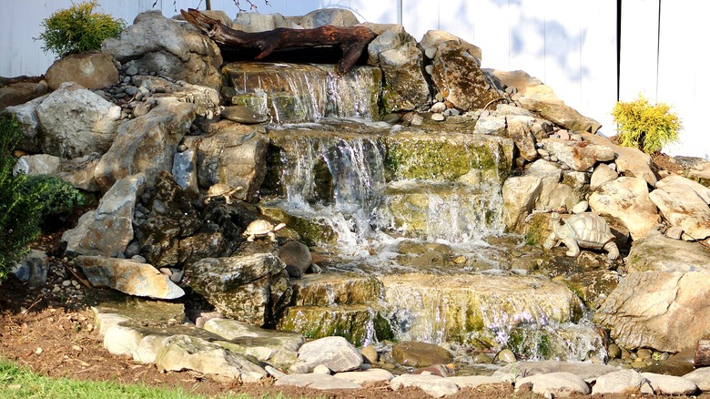 A small pondless waterfall is flowing in a yard