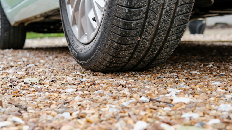 Close-up shot of a car tire parked on a gravel driveway