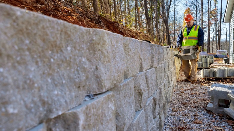A worker constructing a retaining wall in the backyard of a home