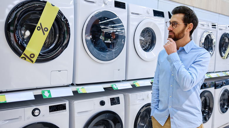 Man standing in front of a row of washing machines at a store