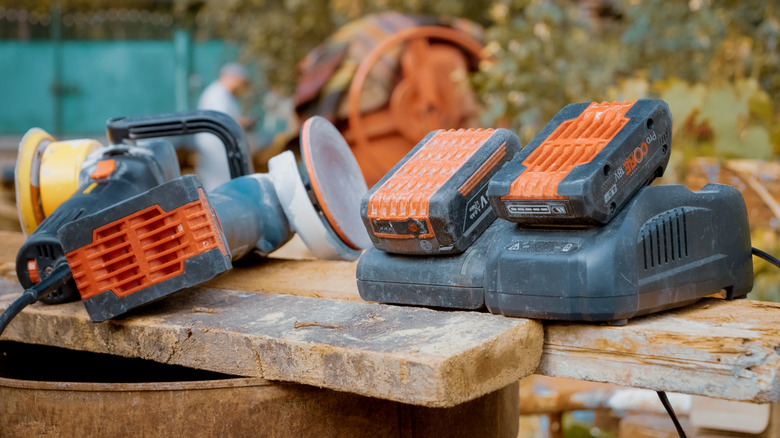 Two  power tool batteries charging on a dusty bench outside