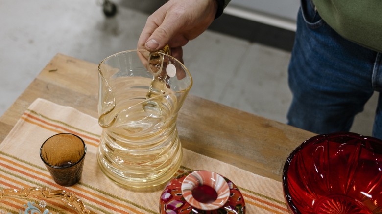 Woman referencing book on a table filled with vintage glassware.