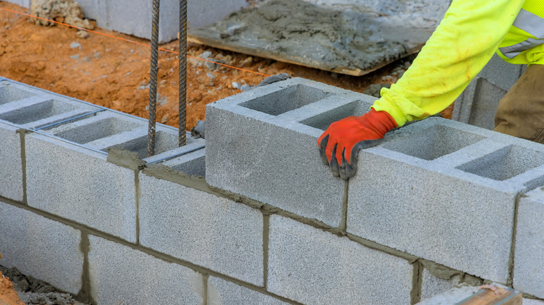 Person stacking a hollow concrete block into a wall