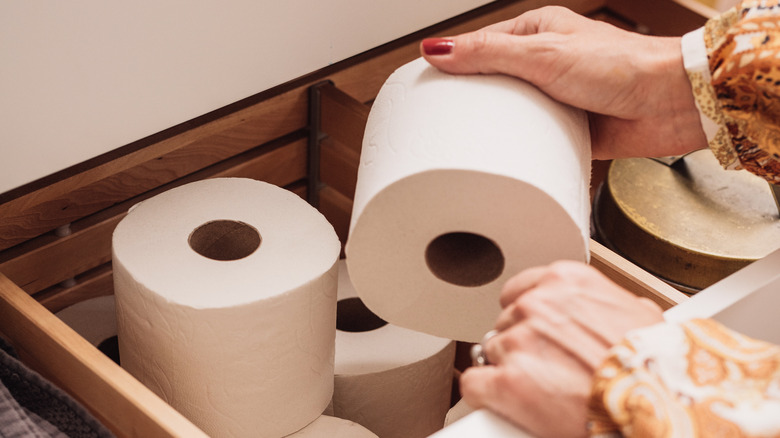 A person putting rolls of toilet paper into a drawer