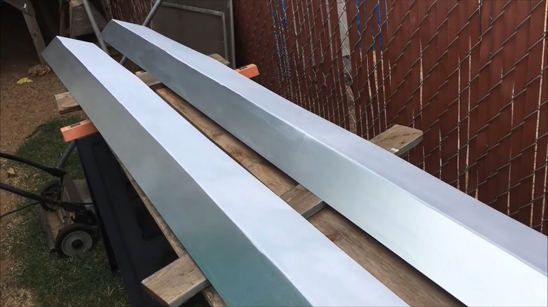 Two strips of metal flashing lying on a wooden bench.