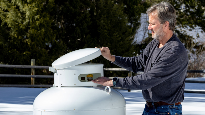 Man reading propane tank gauge in winter