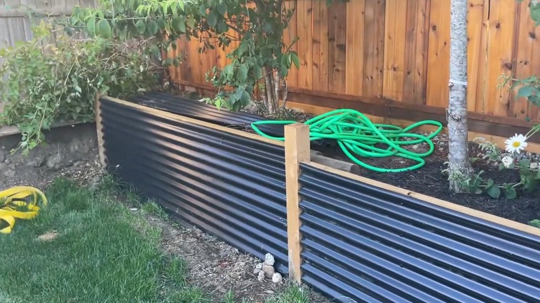 A retaining wall that's built with wood and corrugated metal roofing sheets