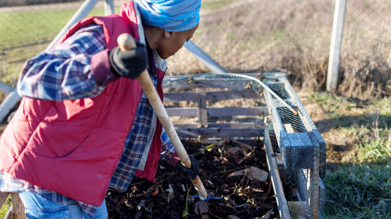 Woman turning a compost heap with a pitchfork