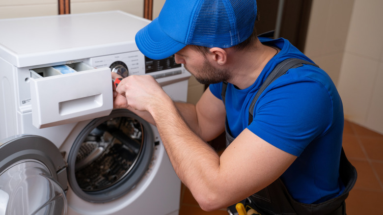 Man fixing a broken washing machine