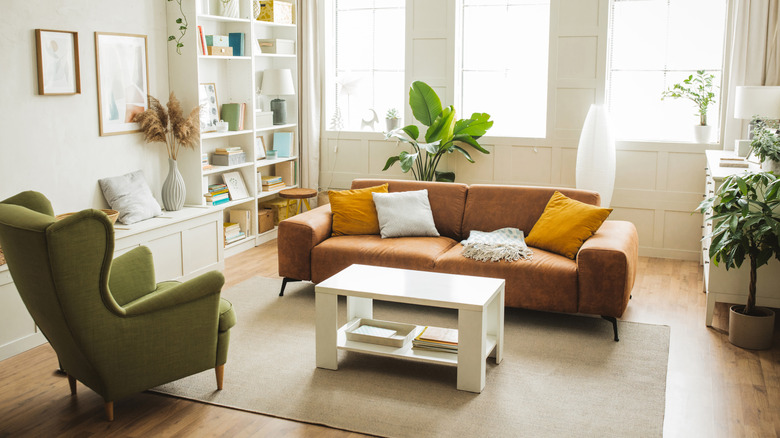 Minimalist living room with a green arm chair and brown leather couch