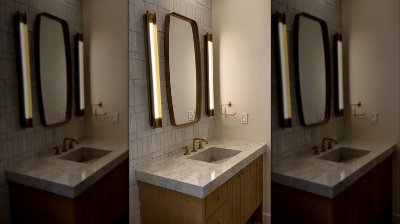 Bathroom counter made of Taj Mahal porcelain, with wood cabinets underneath and gold fixtures