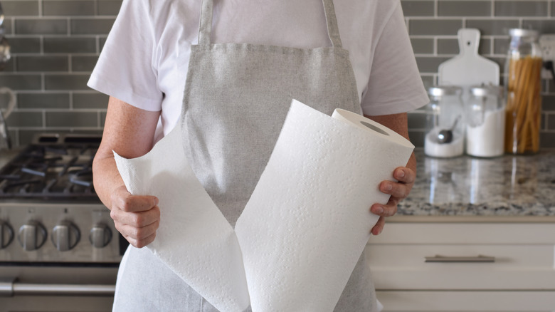 Woman tearing sheet off a roll of paper towels in kitchen