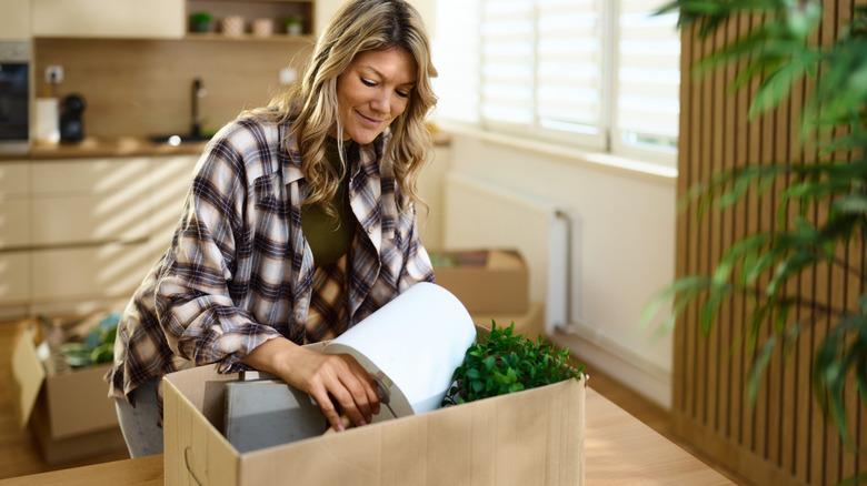 Woman placing a lamp into a cardboard box