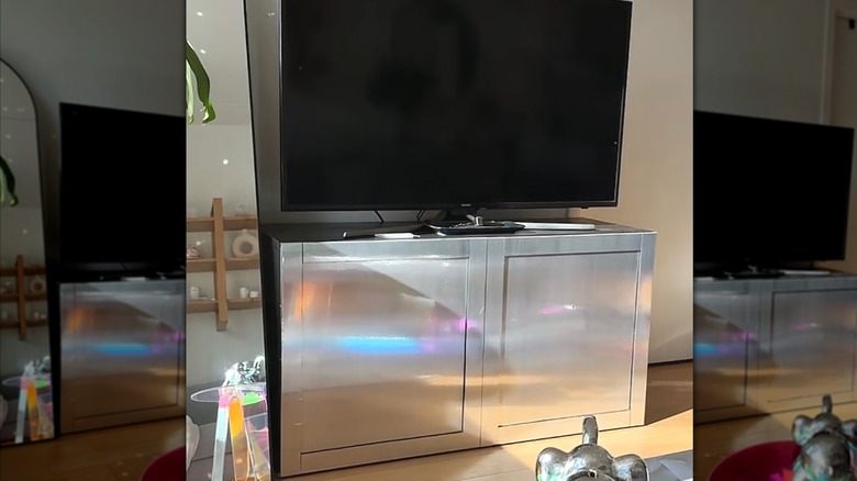 TV stand cabinet that has been refurbished with peel and stick stainless steel contact paper.