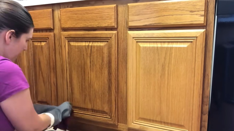 Person staining honey oak wood cabinets
