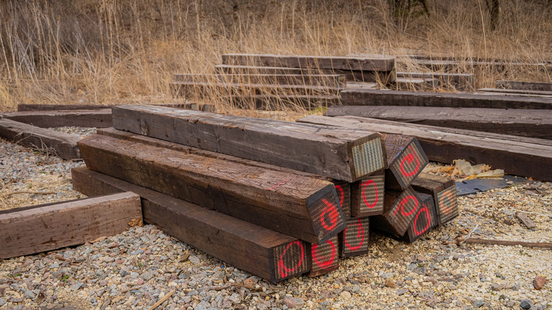 Stacks of weathered railroad ties piled up on a work site.