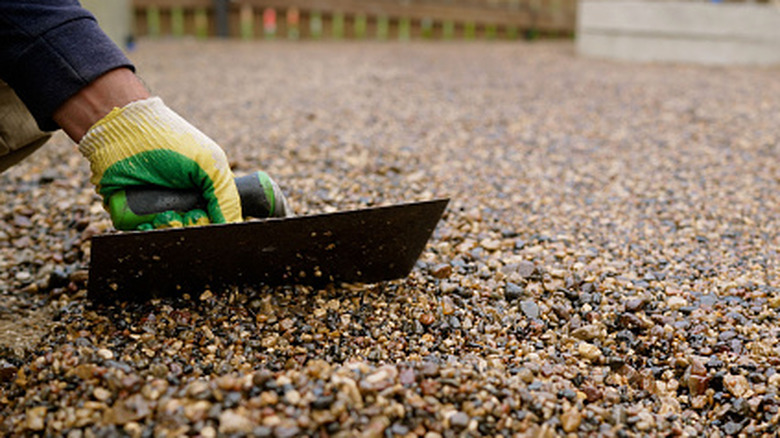 A person using a scraper to level out a gravel driveway