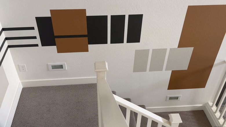 A stairwell landing with a color block pattern featuring shades of gray, brown, and black on a white background