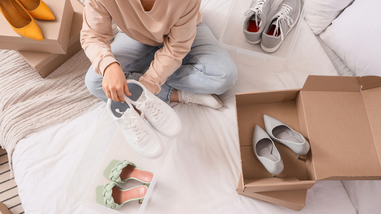 A person sorting out their shoes on their bed