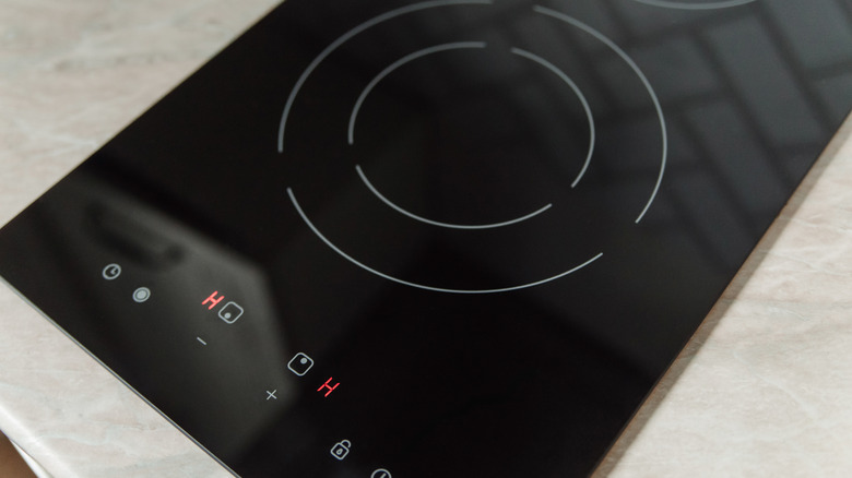A black electric stovetop installed on top of white countertops.