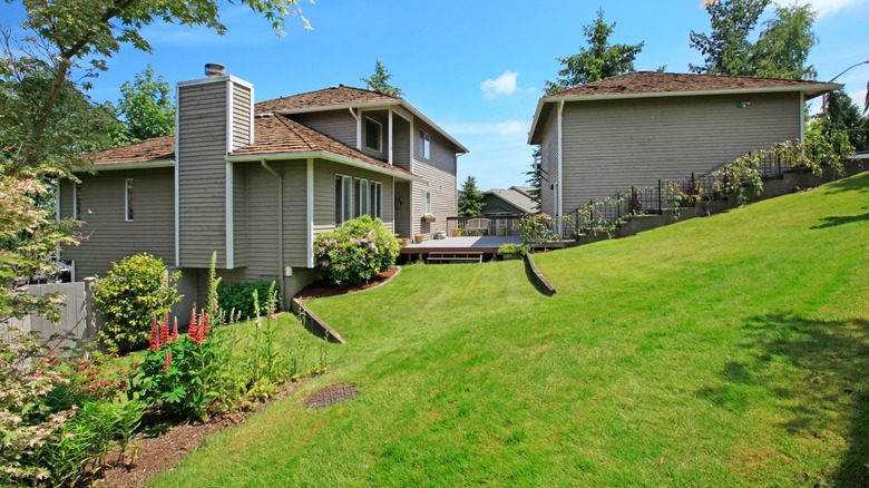 Houses next to a sloped green yard with retaining walls