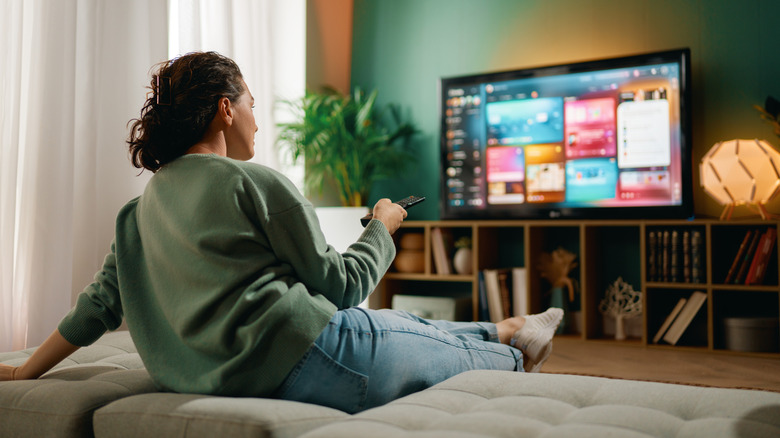 A person pointing a remote at a TV with multiple apps on the screen
