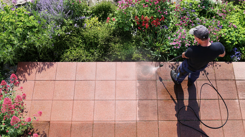 Man washing a paver patio with a pressure washer