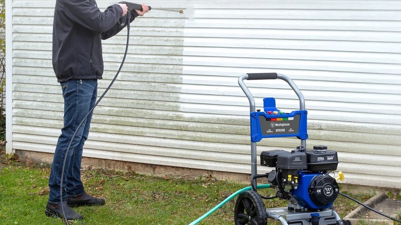 Man pressure washing siding with a Westinghouse gas model