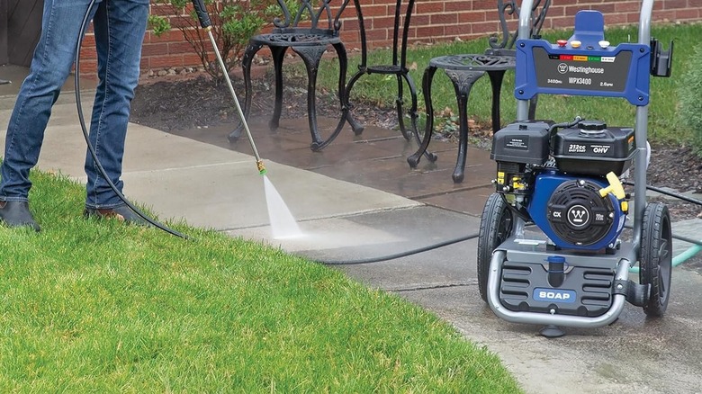 Person using a Westinghouse pressure washer on a sidewalk