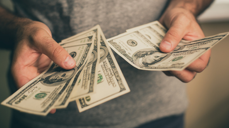 Man holding dollar bills in both hands and counting them