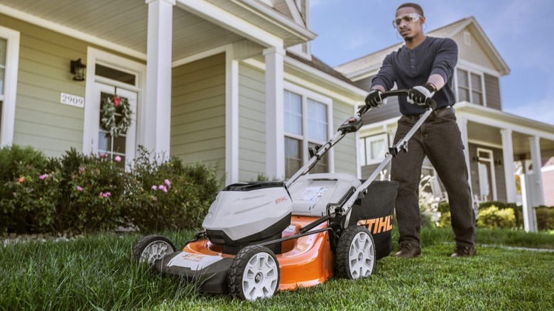 A man pushing a Stihl mower in his lawn